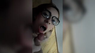 Jolie femme avec des lunettes prend une éjaculation faciale rapide